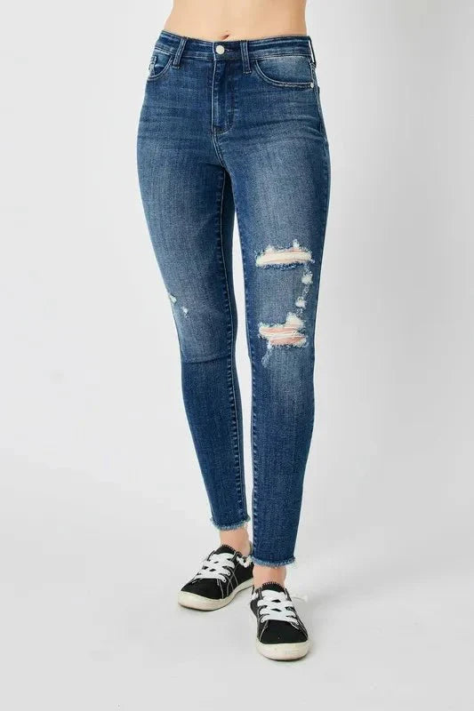 Dark high-waist skinny jeans with stacked rips near the knee
