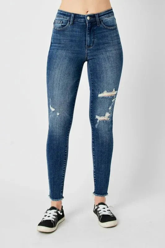 Dark high-waist skinny jeans, distressed patches on the right thigh