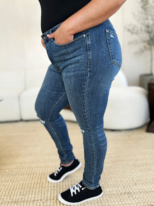 Side view slim jeans in dark wash, knee rips and frayed hem edge
