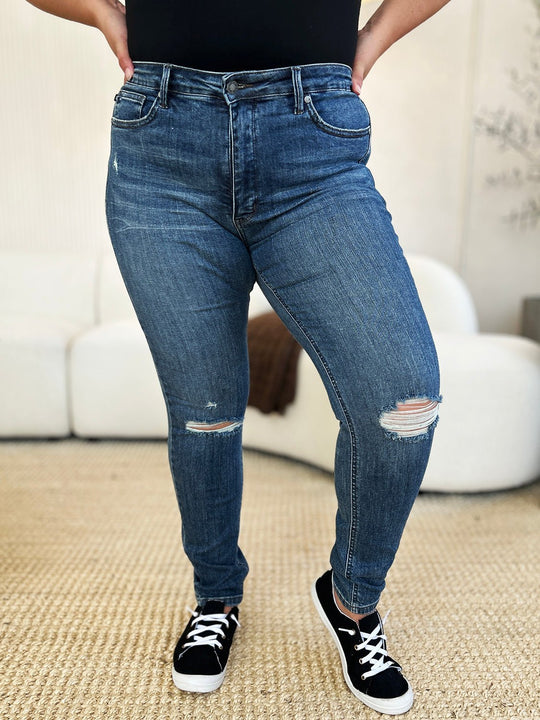 Mid waist slim jeans in dark wash, knee distress and ripped hem detail