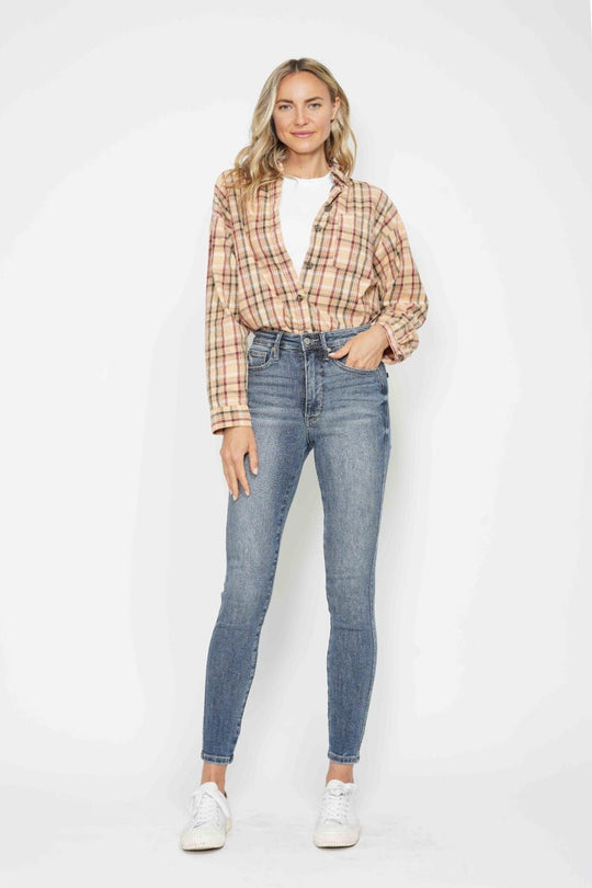 Model in medium wash skinny jeans with slim fit and cuffed ankle hem