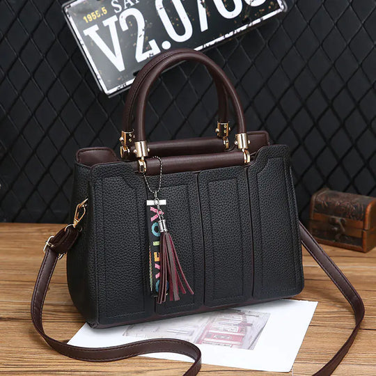 Black shoulder tote with structured front panels, gold-tone hardware, crossbody strap