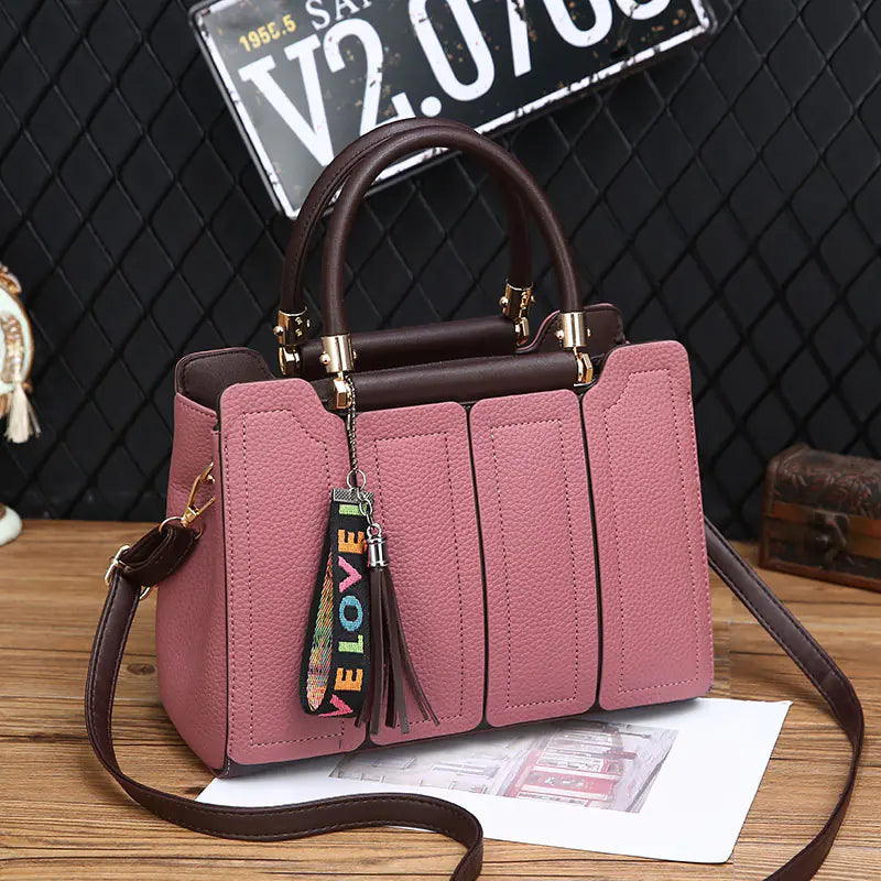Pink fashion shoulder tote with brown top handle, tassel charm, segmented four-panel front