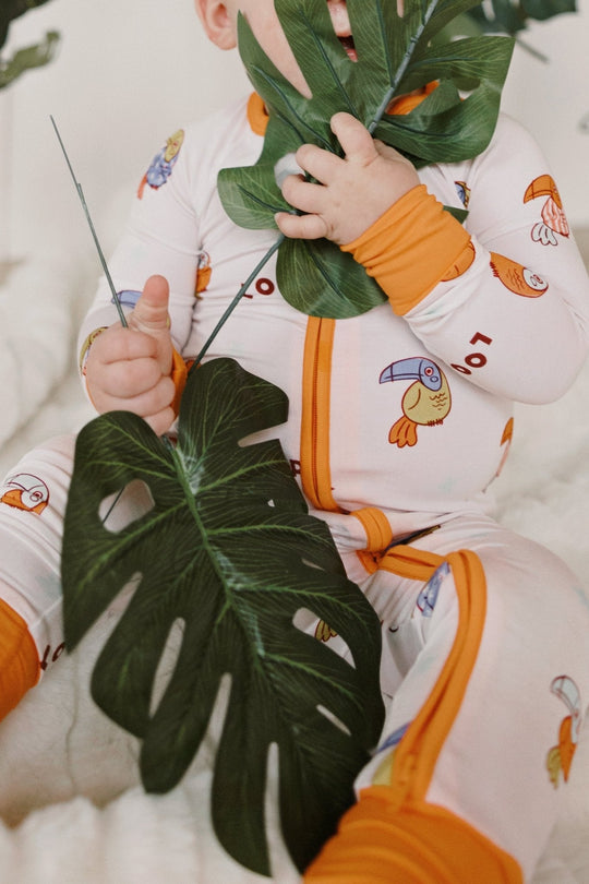Loopy Zipper Romper in white with orange cuffs and front zip, all-over bird pattern