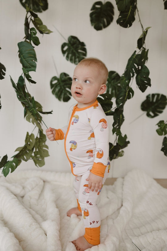 Loopy Zipper Romper in white with orange trim and colorful bird print, full-body coverage