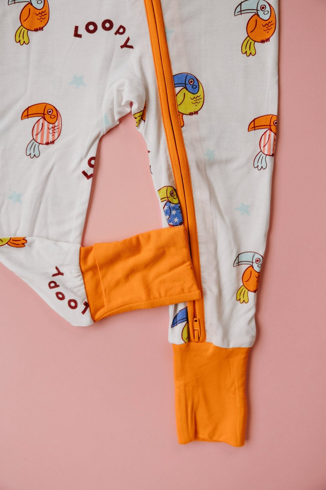 White zip romper with orange foot cuffs and loop bird print