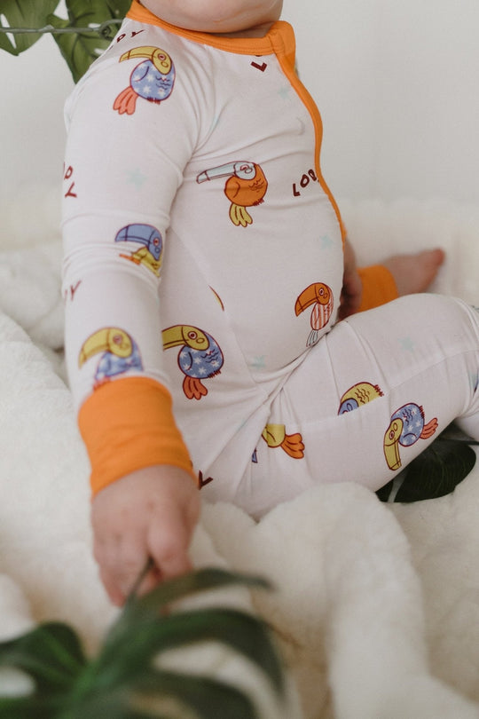 White romper with orange trim and loop bird print, long sleeves and legs