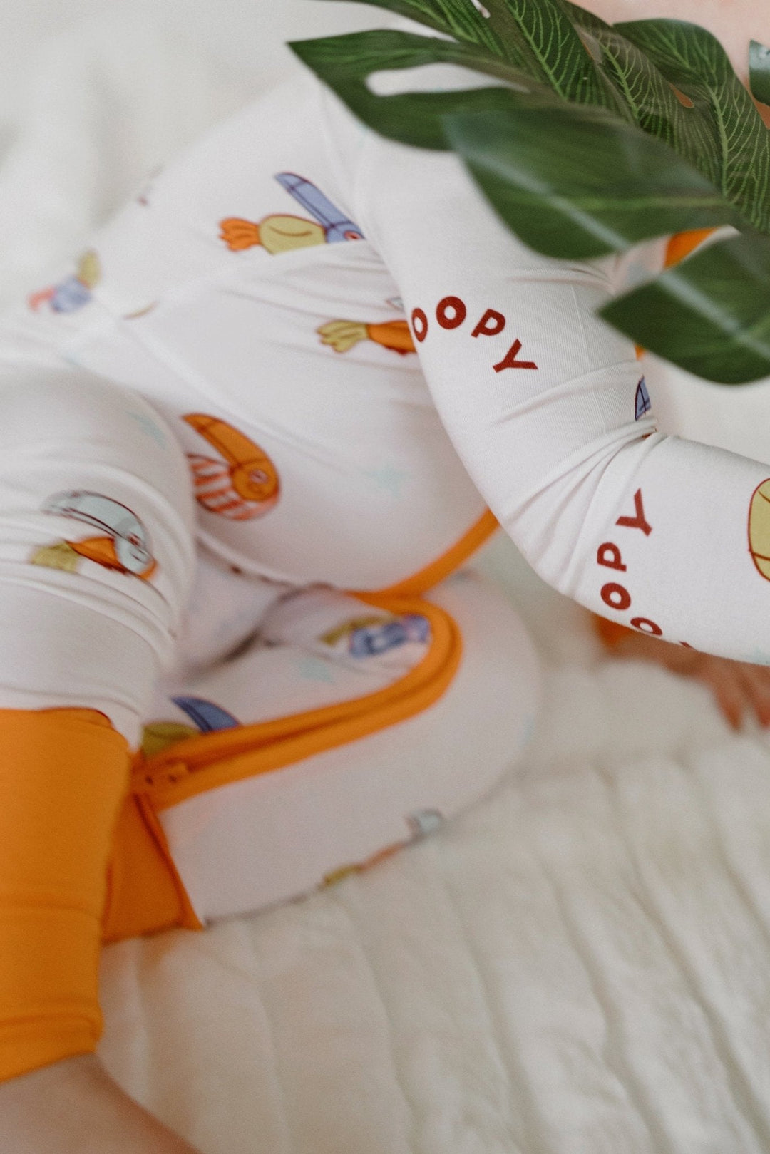 Close-up leg: white romper with orange trim and repeating bird print