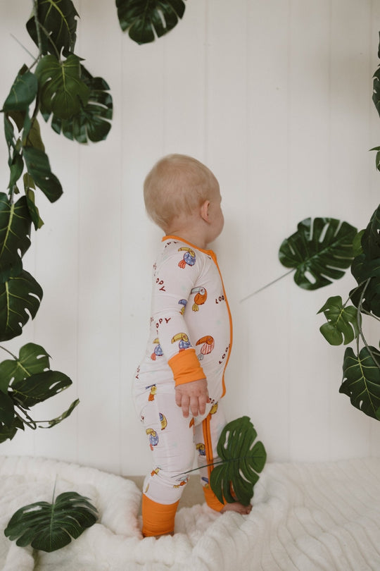 Loopy Zipper Romper back view in white with orange cuffs and bird print