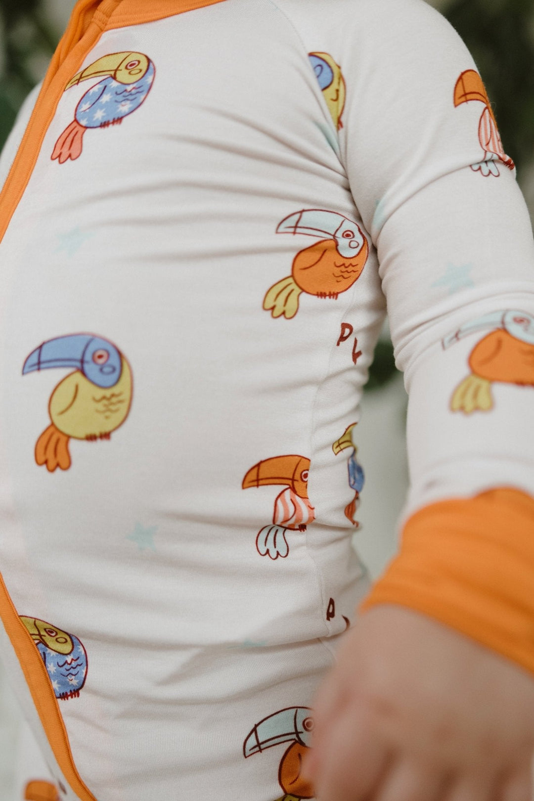 White romper with orange-trim zipper and blue, yellow, orange bird graphics
