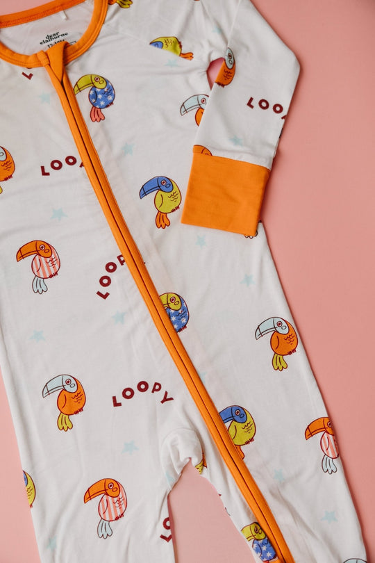 Front view: white romper with orange zipper trim, orange cuffs, and colorful bird print