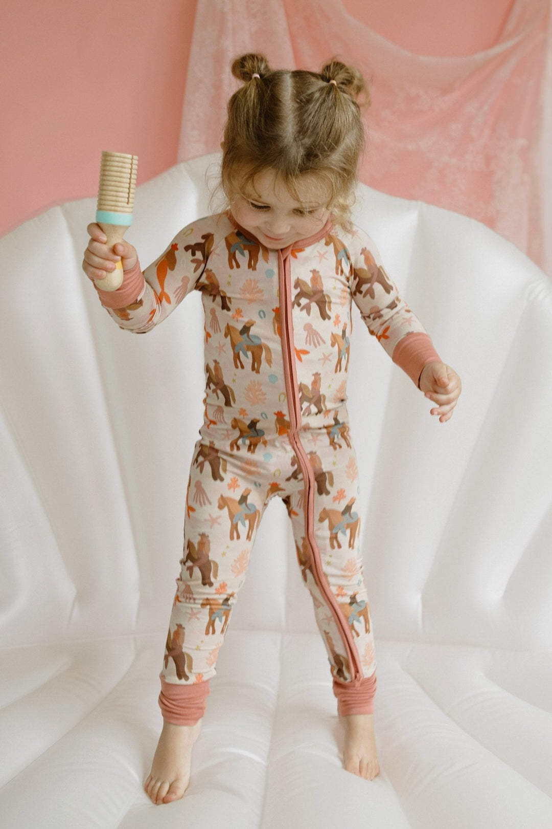 Mermaid zipper romper worn by child, long sleeves, front zip, and pink-trim cuffs