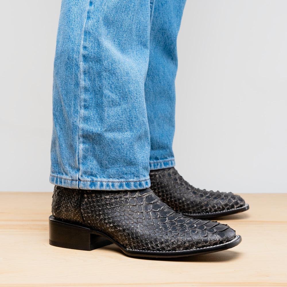 Black western boot shown with blue jeans; low stacked heel and textured toe