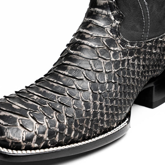 Close-up of black western boot shaft with textured scale pattern and stitch detailing