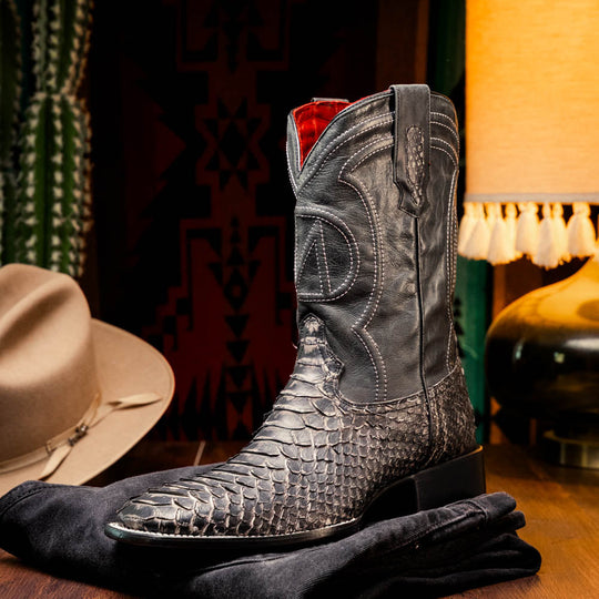 Black western boot paired with jeans; high shaft, stitched patterns, and red lining