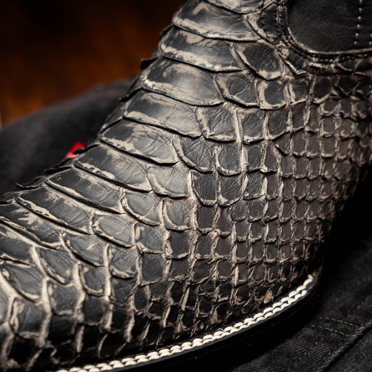 Side view close-up of black textured boot with white trim and stacked stitching lines
