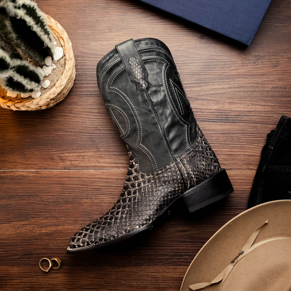 Black western boot on wood floor; pointed toe, stacked heel, and stitched shaft