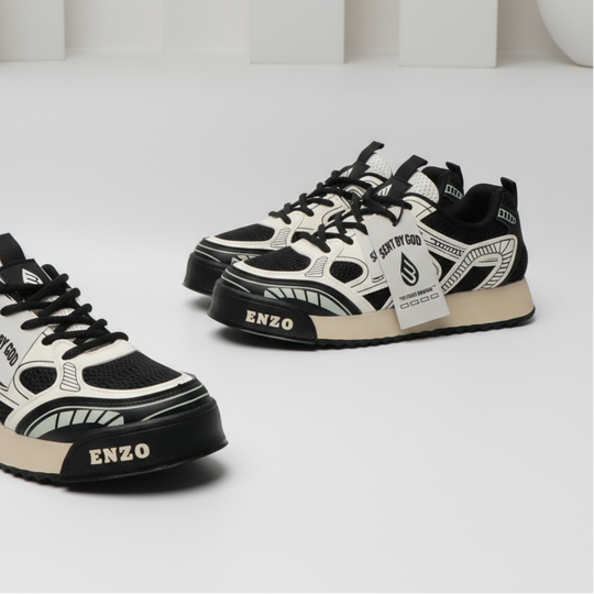 Two milk-white lace-up sneakers with black graphic overlays and hanging tongue tag