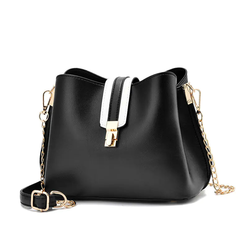 Black bucket bag with white strap detail, gold hardware, and chain crossbody strap
