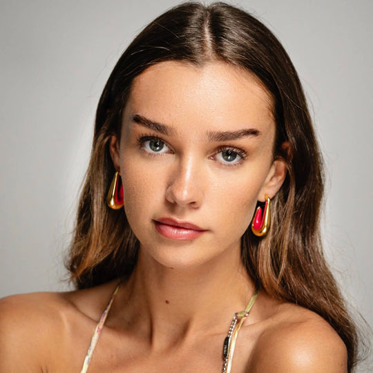 Drop hoop earrings with gold-tone hoops and red-pink enamel inner, worn