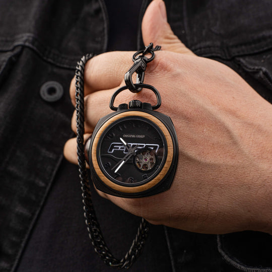 Reloj de bolsillo vintage con cadena negra en la muñeca; caja negra y borde de madera.