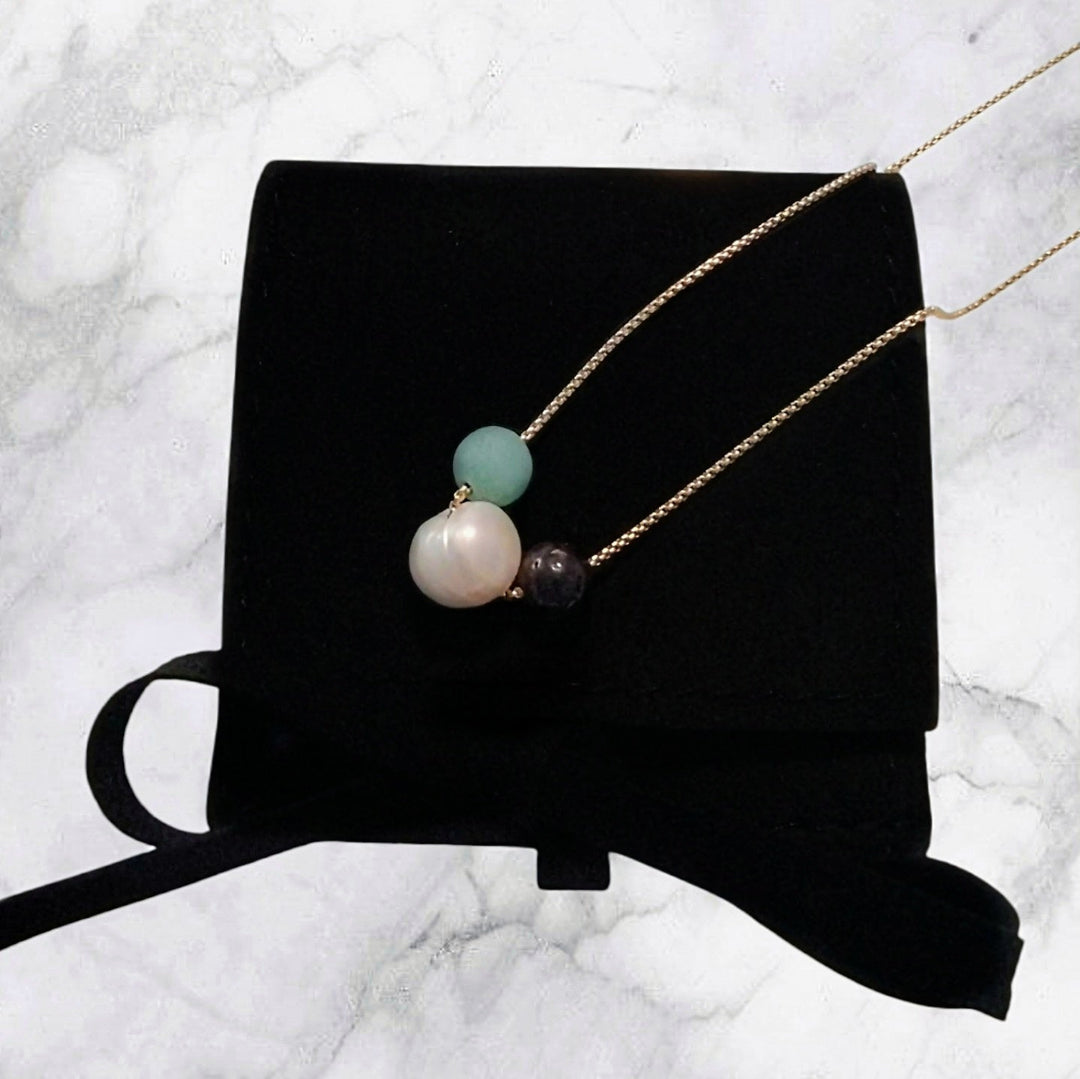 Gold chain necklace featuring round beads: white pearl, turquoise, and dark stone beads