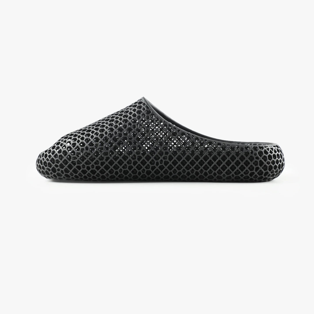 Black 3D-printed slipper, side view with open toe and honeycomb hex pattern upper