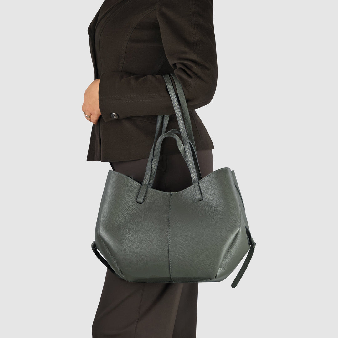 Dark grey calf leather tote bag carried by model, wide handles and drawcord top.