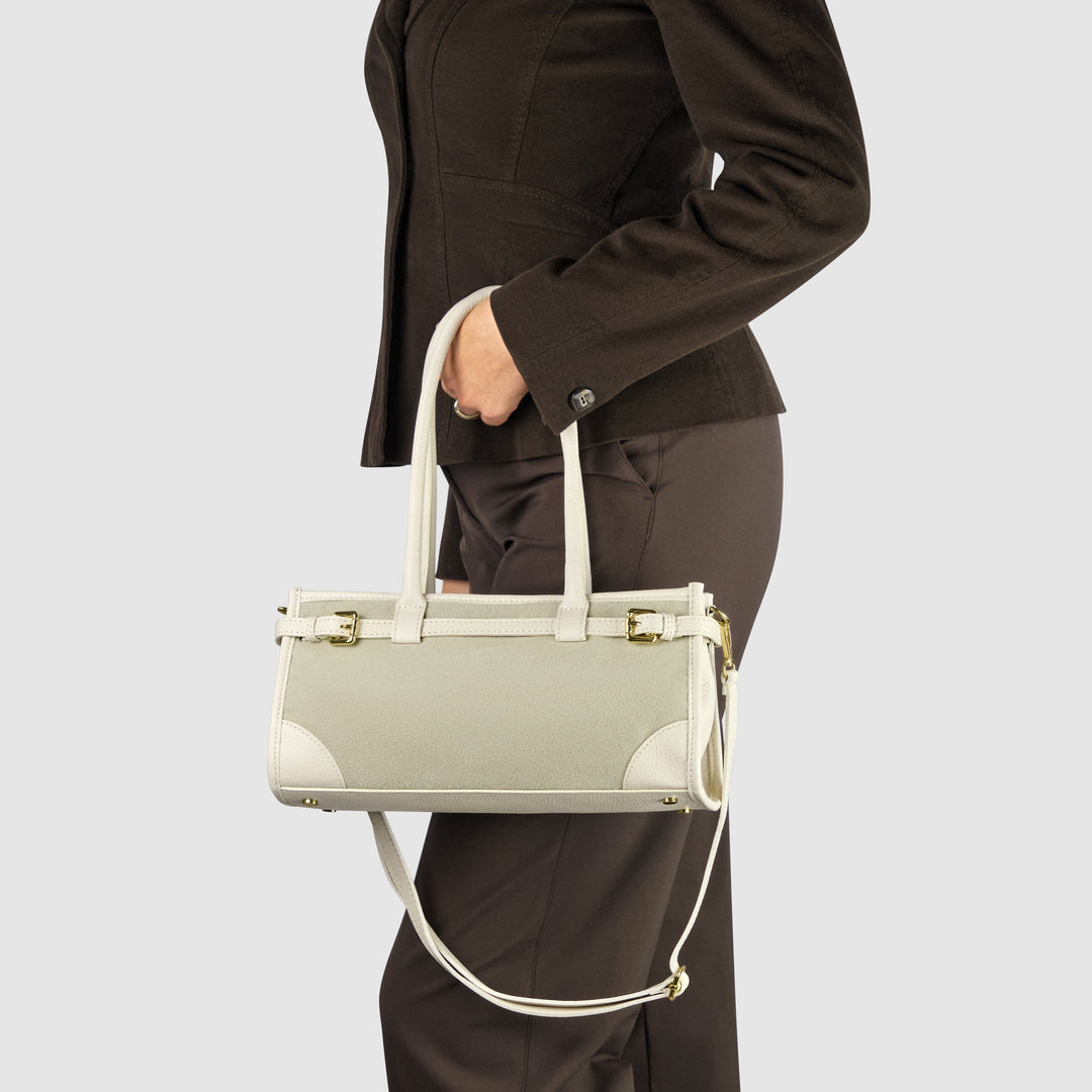 Beige shoulder bag worn on person; gold-tone buckles, side rings, adjustable strap