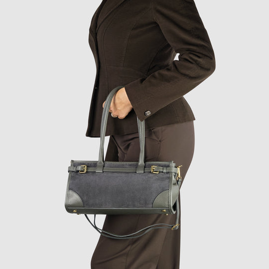 Dark grey shoulder bag worn on person; gold-tone buckles and crossbody strap hardware