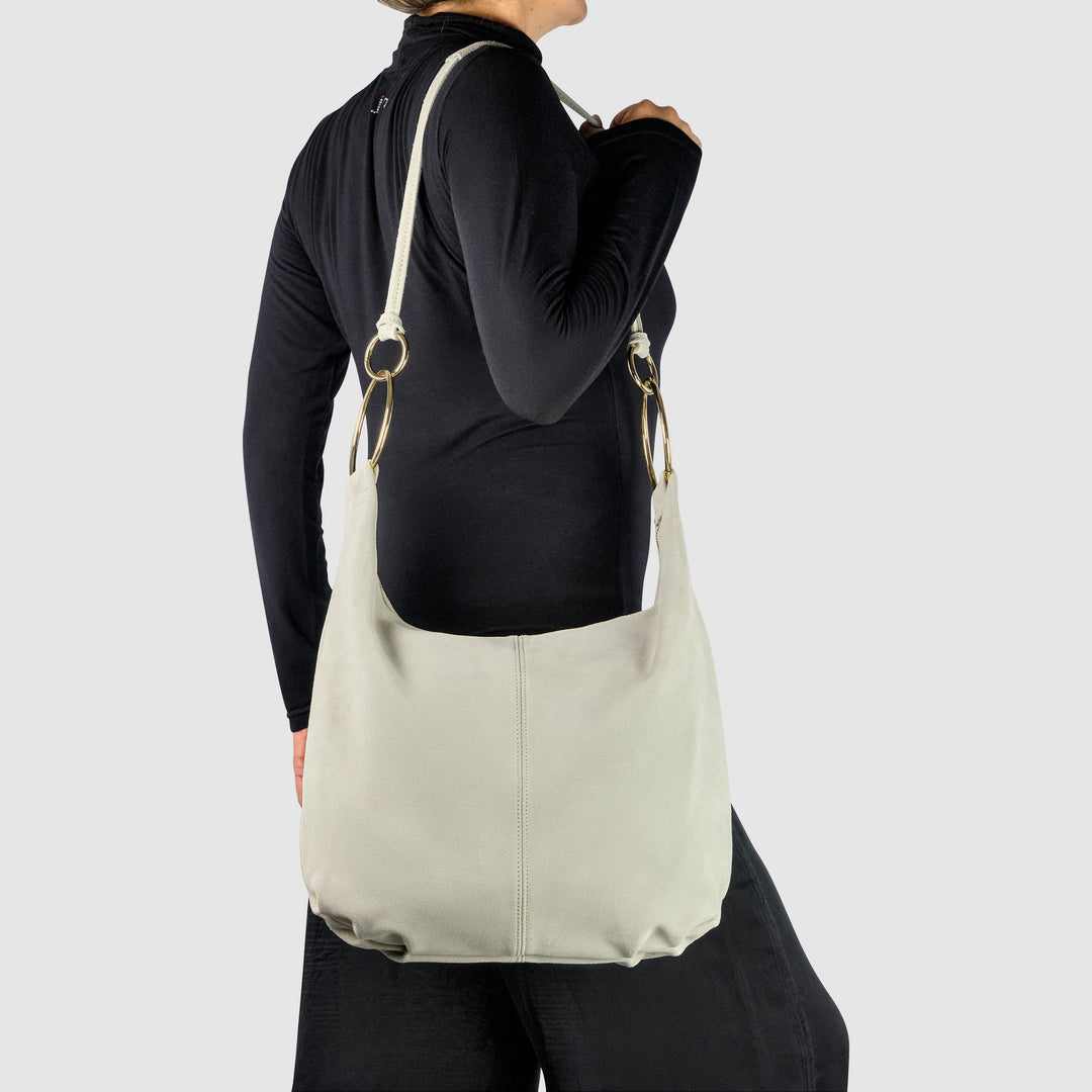 Cream suede hobo bag worn by model, showing gold-tone ring strap hardware
