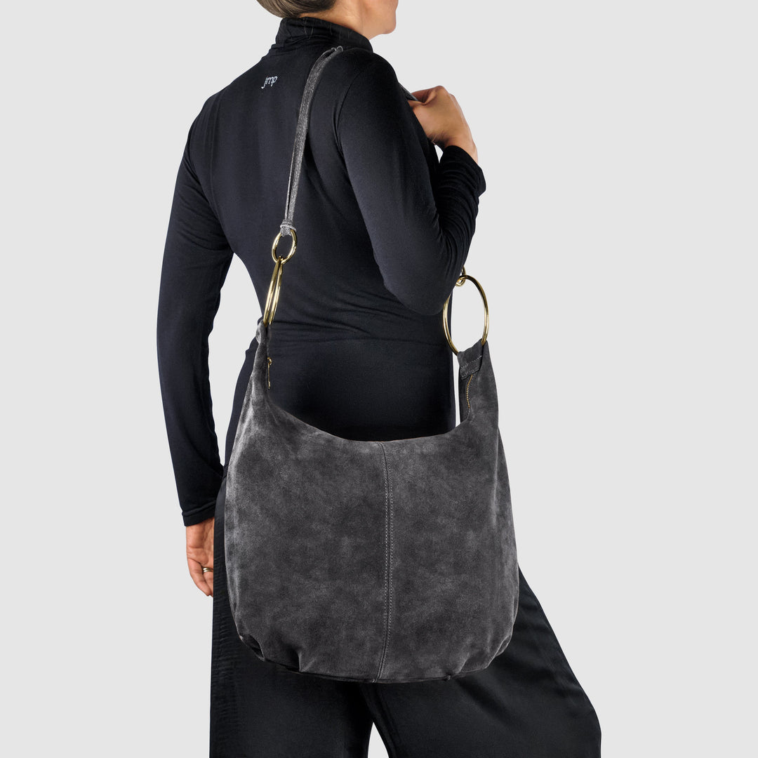 Dark suede hobo bag worn on shoulder, gold-tone ring handle details