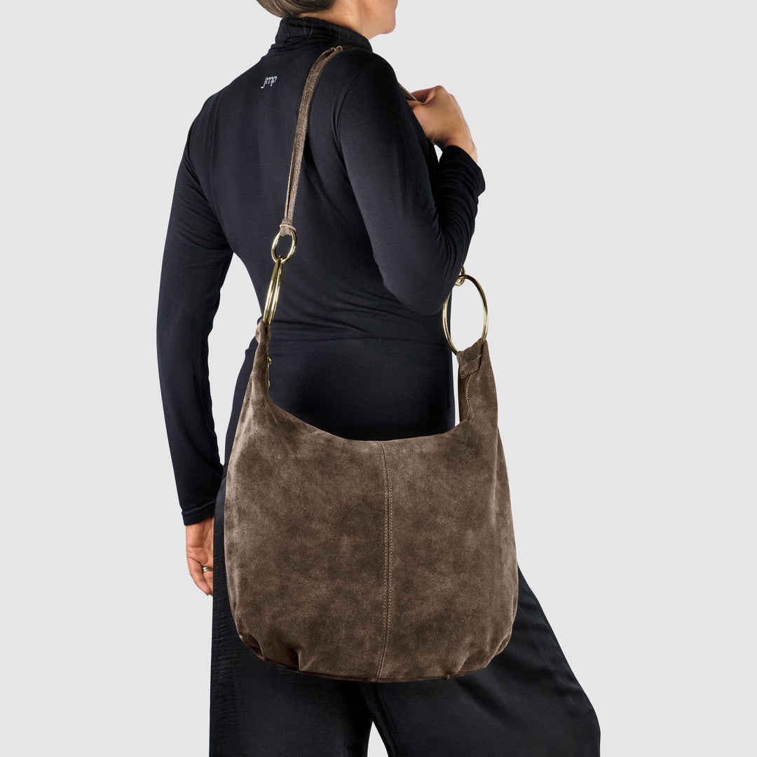 Brown suede hobo bag worn on shoulder, gold-tone ring handle hardware