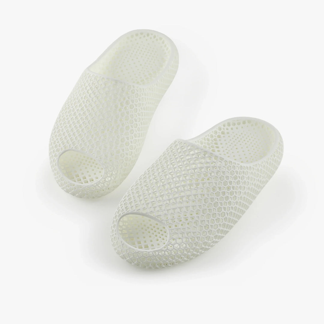 White 3D-printed slippers, angled pair with open toe and raised honeycomb texture