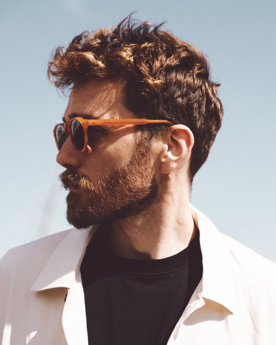 Tribe sunglasses with orange-brown frame and green-tinted lenses worn